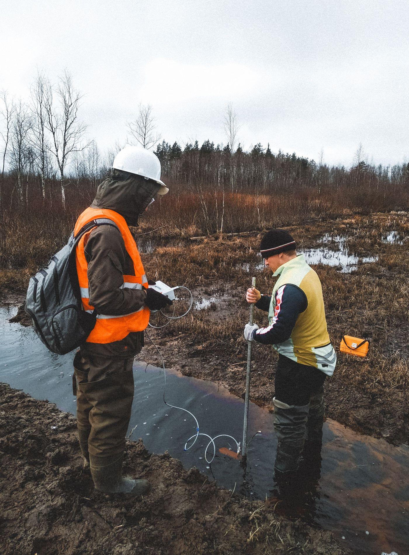 Two researchers wading through shallow water taking on-site water quality readings